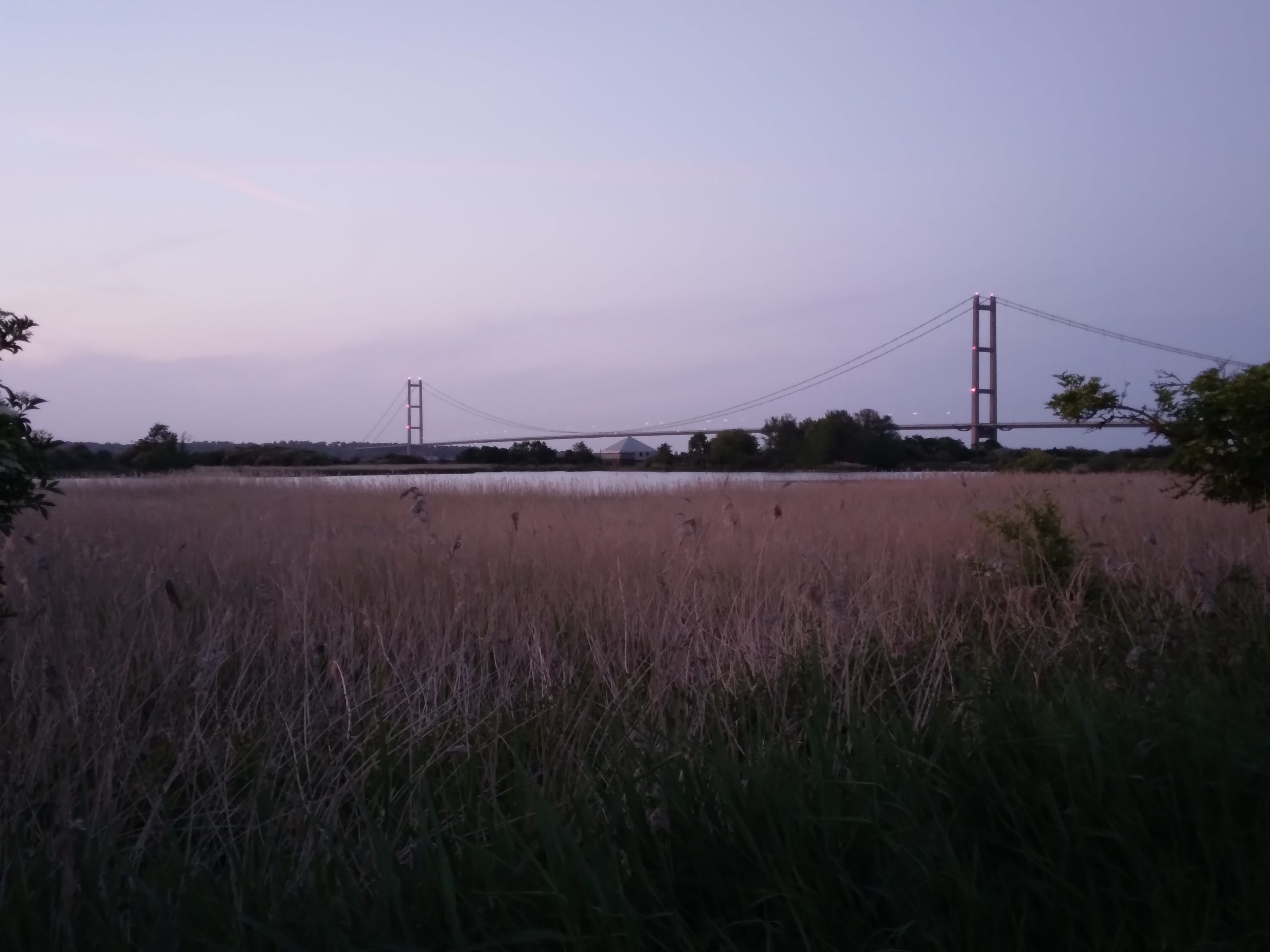 The Humber Bridge seen across water and reedbeds at Far Ings Nature Reserve